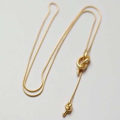 Goudkleurige ketting met sierlijke knoop, minimalistisch design. Fijne schakelketting met elegant slotje, perfect als trendy accessoire. Ideaal voor een stijlvolle, moderne look.